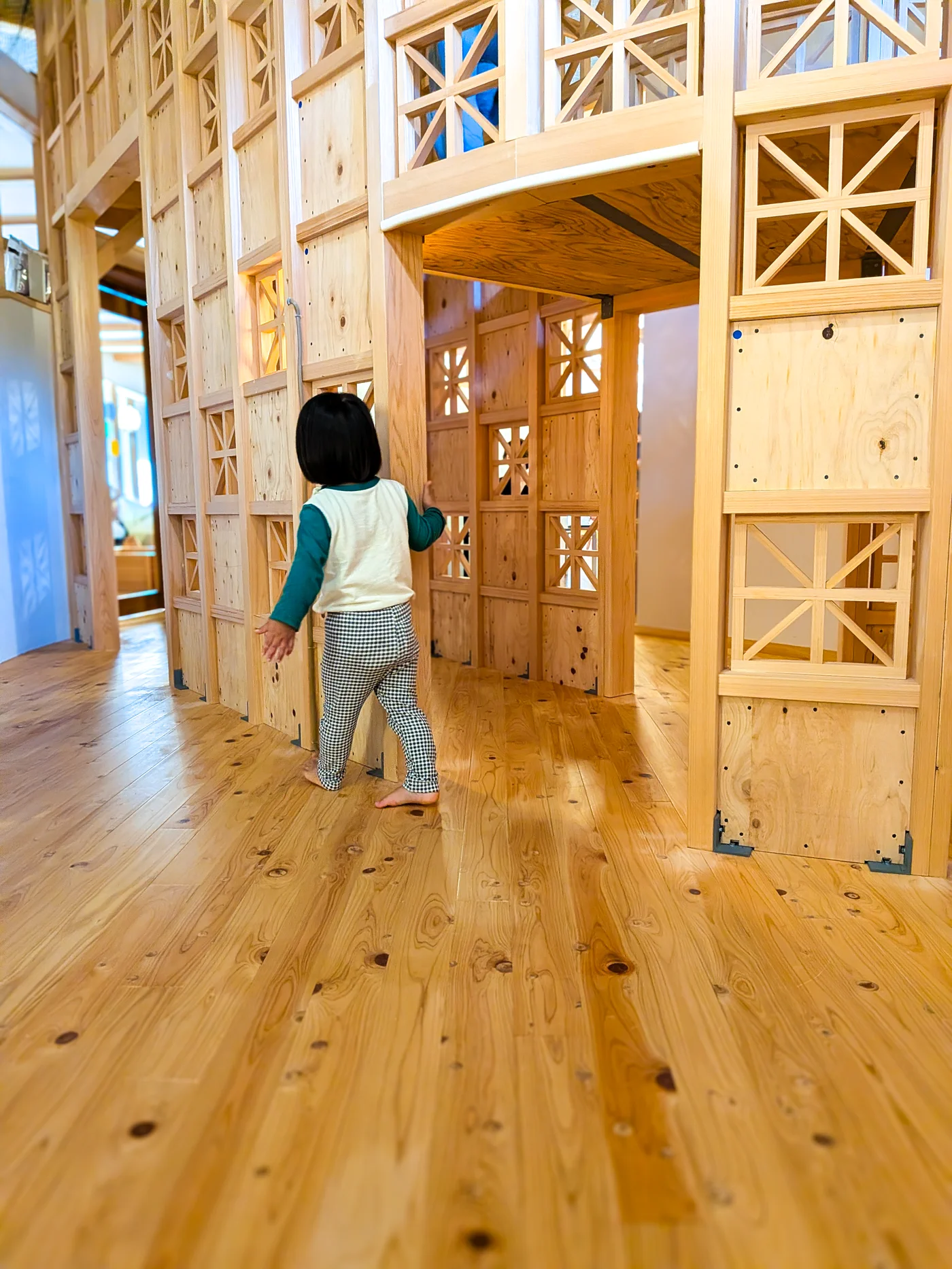 大きな木製遊具の中を探検する子ども